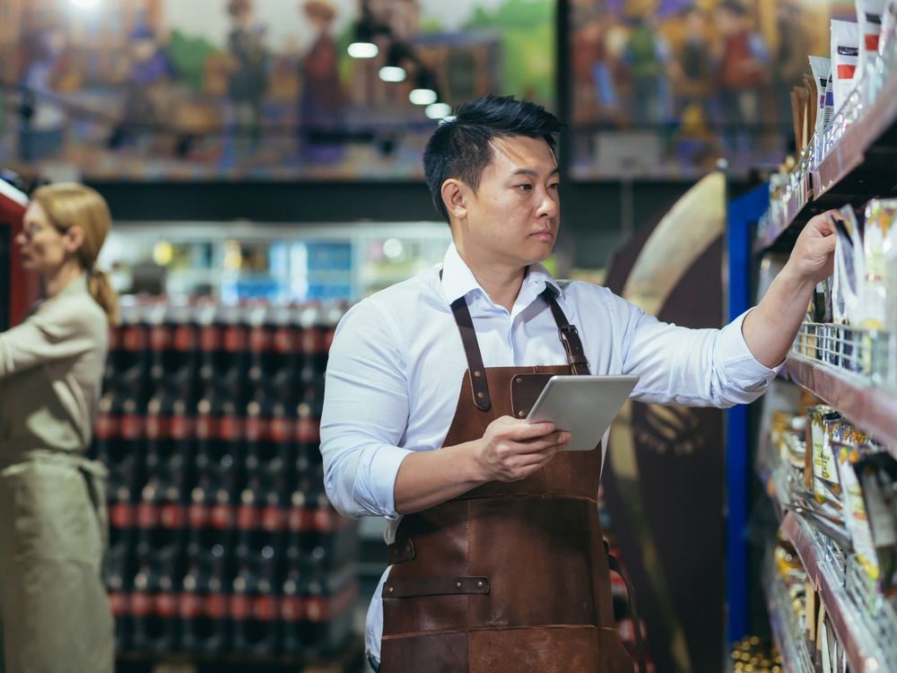 Quản lý cửa hàng kiểm tra quầy kệ bằng máy tính bảng trong siêu thị
