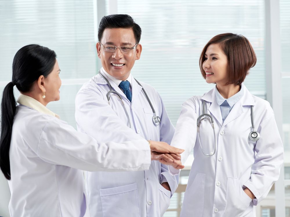 Đội ngũ bác sĩ đặt tay lên nhau thể hiện tinh thần đồng đội trong bệnh viện